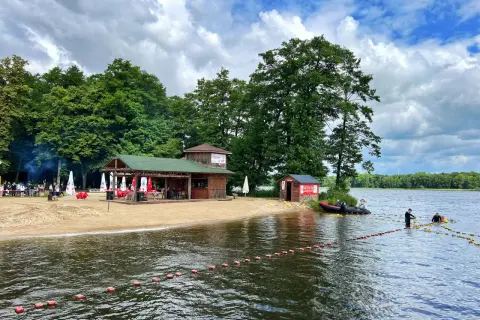 Plaża nad jeziorem w Szczecinku z barem i ratownikami przygotowującymi boje.