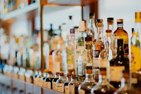 Rząd butelek z alkoholami, niektóre z etykietami wskazującymi, ile likier ma procent.