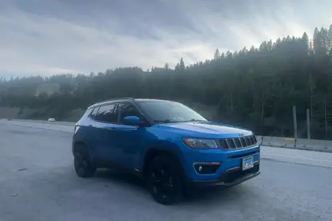 Blå Jeep Compass står vid vägkanten med en skog i bakgrunden. Kanske ett oväntat stopp, en Jeep Compass problem?