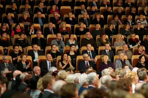 Elegancko ubrani widzowie siedzą w filharmonii, zastanawiając się, jak się ubrać do filharmonii.