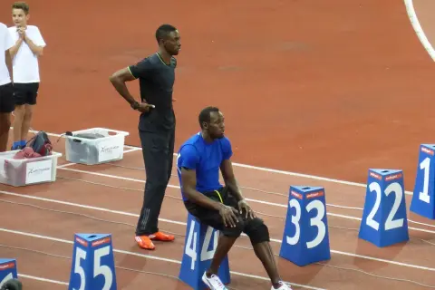 Usain Bolt, siedzący i stojący na bieżni, przypomina o jego rekordowej prędkości, która osiągnęła ponad 44 km/h.