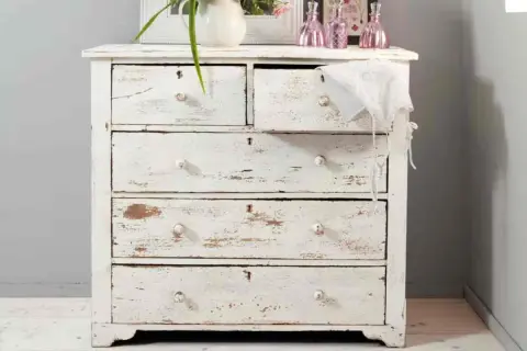 Comò in legno decapato bianco, con cassetti consumati che raccontano storie di un tempo.