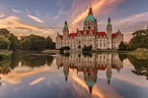 Nowy Ratusz w Hanowerze, jeden z najpiękniejszych zamków w Niemczech, odbija się w spokojnej tafli jeziora o zachodzie słońca.