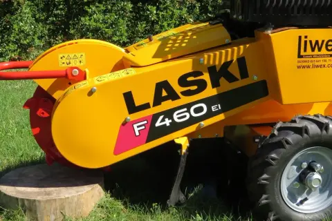 Żółty frez do pni drzew LASER F460 EI z czerwonym uchwytem i tarczą tnącą, gotowy do pracy na trawie.