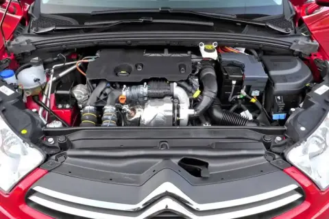 Silnik w czerwonym Citroen C4 2008. Widok komory silnika z turbosprężarką i przewodami.