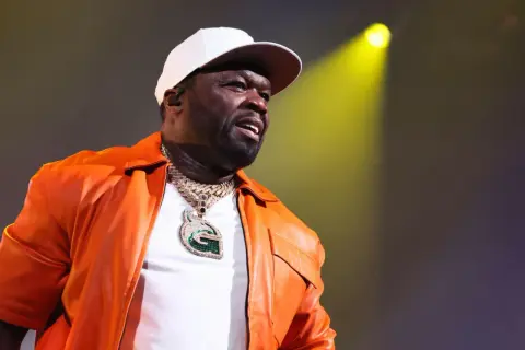 50 Cent w pomarańczowej kurtce i białej czapce, z błyszczącym naszyjnikiem. Bilety na jego koncert rozchodzą się jak ciepłe bułeczki.