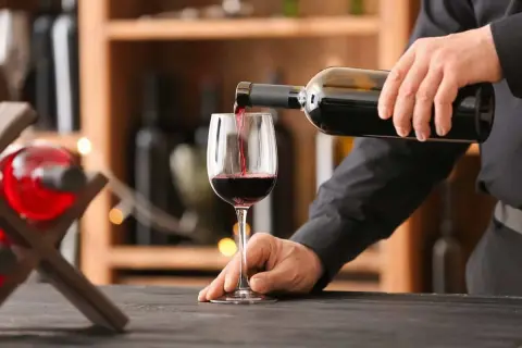 Versando vino rosso in un bicchiere, si notano i difetti del vino: torbidità e sedimenti.