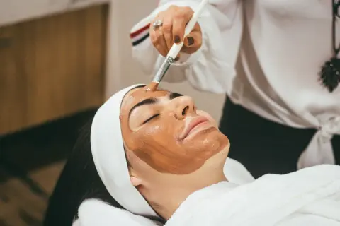 Application d'un masque sur le visage, étape clé d'un massage lymphatique visage relaxant.