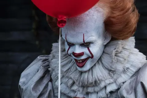 Przerażający klaun Pennywise, znany ze slasherów, trzyma czerwony balon.
