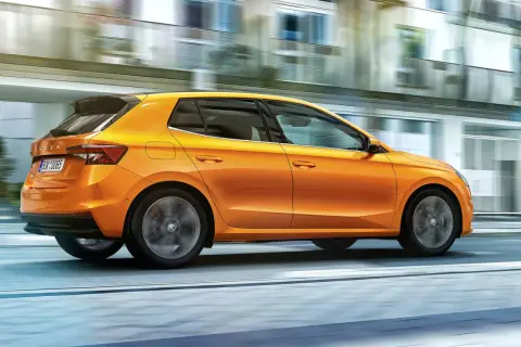 En orange Skoda Fabia kör snabbt genom staden. Inga problem med denna bil, bara ren körglädje.
