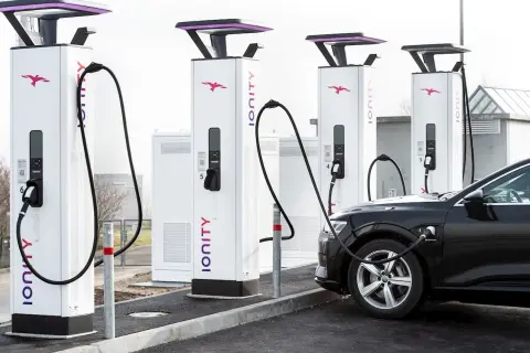 Une voiture électrique noire est branchée à une borne de recharge Ionity. Plusieurs bornes sont alignées, prêtes à alimenter les véhicules.