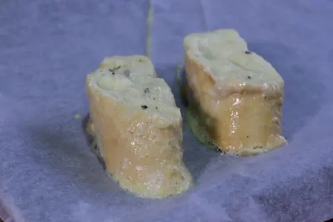 Dos trozos de pan empapados en huevo y leche, listos para hornearse como torrijas.