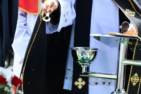 Osoba w szatach liturgicznych sypie ziarna. Czy to apostata, kto to? Ceremonia z mikrofonem i kielichem.