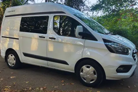 Furgoneta blanca Ford Transit tamaño mediano, lista para la aventura.