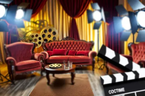 Ambiance de rêve pour une décoration thème cinéma à faire soi-même : fauteuils velours rouge, bobines de film, spots et claquette.