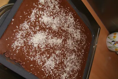 Schokoladenkuchen mit Kokosraspeln bestreut, bereit für einen Klecks saure Sahne.