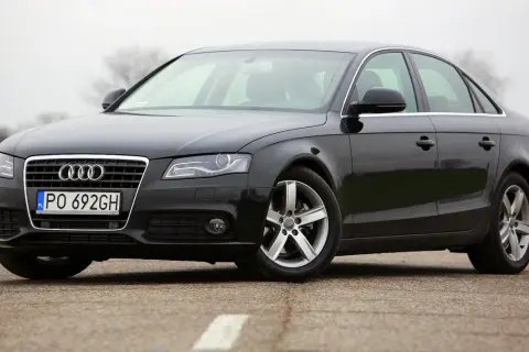 Czarne Audi A4 B8 z polskimi tablicami PO 692GH, z nowymi żarówkami w reflektorach, stoi na drodze.