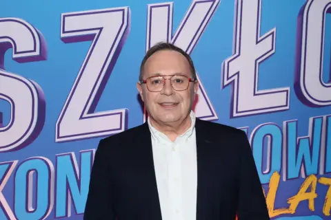 Uśmiechnięty mężczyzna w okularach na tle napisu "SZKŁO KONTAKTOWE OBSADA".