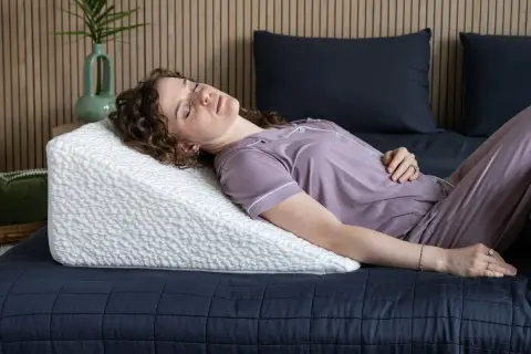 Woman sleeping on a wedge pillow. Learn how to make memory foam pillow expand faster for ultimate comfort.
