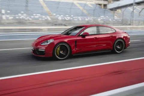 Czerwone Porsche Panamera GTS pędzi po torze wyścigowym, za nim widać trybuny.