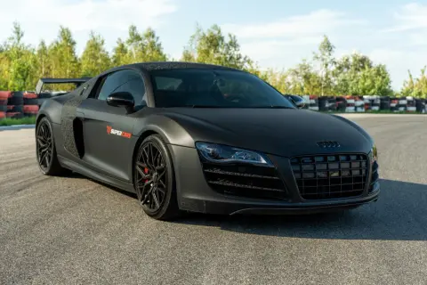 Matowy czarny Audi R8 V10 z czerwonymi zaciskami hamulcowymi na torze wyścigowym.