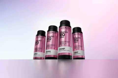 Cuatro botellas de baño de brillo para el pelo Redken Shades EQ Gloss en tonos perlados y lilas, listas para dar un acabado radiante.