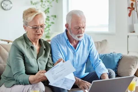 Couple âgé gérant leur compte bancaire, préoccupé par les finances, peut-être lié à l'alzheimer.