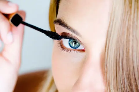 Une femme applique du mascara. Pour savoir comment enlever du mascara waterproof, il faut un bon démaquillant.