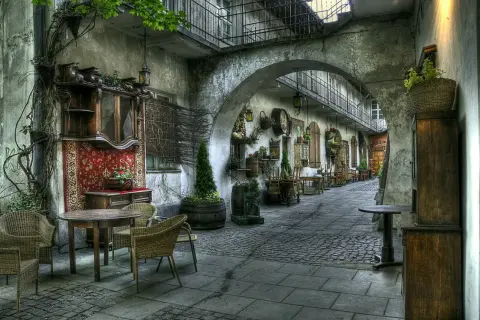 Urokliwy dziedziniec w Krakowie, gdzie antyczne meble i dywany przywołują ducha historii, niczym najcenniejsze zabytki krakowa.