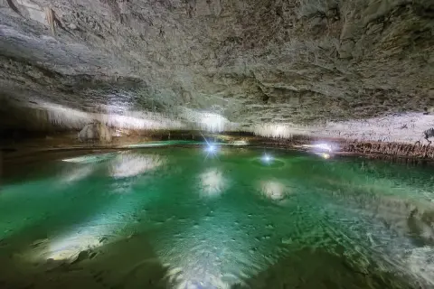 Magnifique lac souterrain aux eaux émeraude, entouré de stalactites, une invitation à **aller aux grottes de Choranche**.