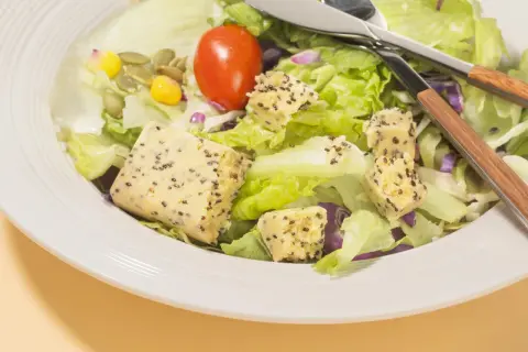 Salade fraîche avec cubes de tofu aux graines, maïs, tomate et graines de courge. Parfait pour savoir que manger après le sport.