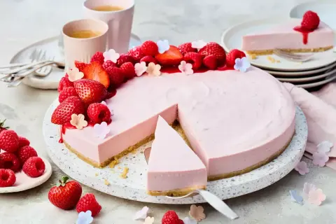 Ein köstlicher Erdbeer-Cheesecake ohne Backen, dekoriert mit frischen Beeren und kleinen Blüten. Perfekt für den Sommer!