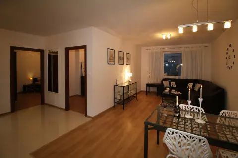 Nowoczesny sufit podwieszany w salonie, z eleganckim oświetleniem, tworzy przytulną atmosferę. Wnętrze jest stylowo urządzone.