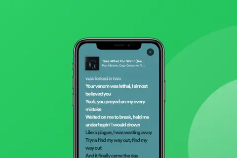 Ekran telefonu z widocznymi tekstami piosenki na Spotify.