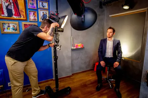 Fotograf robi zdjęcie mężczyźnie w garniturze w studiu fotograficznym.