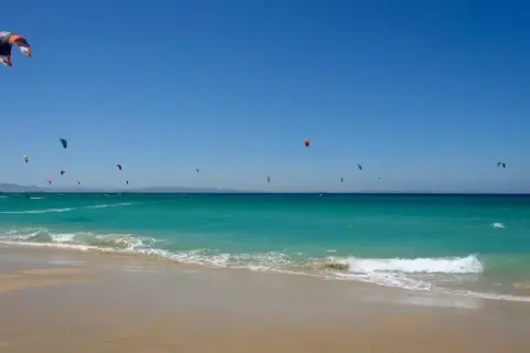 El levante en Tarifa impulsa a numerosos kitesurfistas sobre aguas turquesas. Un día perfecto para disfrutar del mar y el viento.