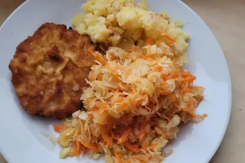 Złocisty kotlet schabowy z ziemniakami i surówką z kapusty i marchewki – idealne połączenie, co pasuje do schabowego.