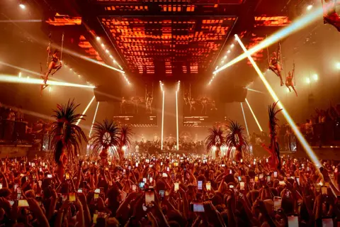 Folla festante con smartphone alzati per catturare lo spettacolo aereo e le performance, un'anticipazione dell'apertura discoteche Ibiza.