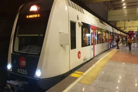 Nowoczesny pociąg metra w Walencji, numer 4335, stoi na peronie. Ludzie czekają na wejście.