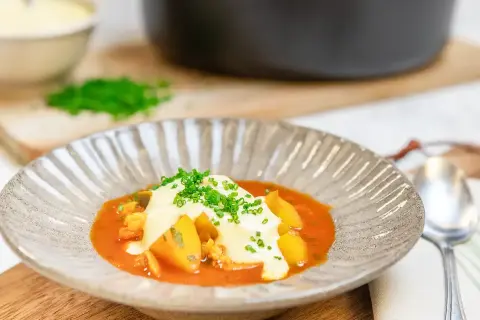 En vällagad fisksoppa med saffran, toppad med krutonger och färska örter. Serveras i en vacker skål med en sked bredvid.