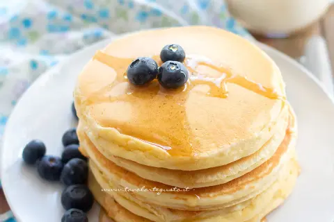 Pancakes soffici con albumi, guarniti con mirtilli freschi e sciroppo d'acero.