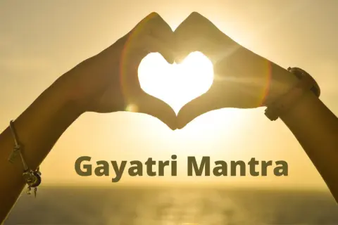 Manos forman un corazón al atardecer, iluminando el significado del Gayatri Mantra.