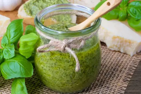Frisches Pesto im Glas, zubereitet mit dem Thermomix, daneben Basilikum, Parmesan und Brot.