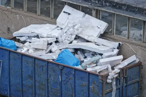 Kontener z odpadami budowlanymi, w tym dużą ilością białego styropianu. To miejsce, gdzie oddać styropian po budowie.