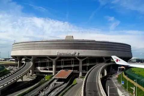 Charakterystyczny Terminal 1 na lotniskach w Paryżu, z krętymi drogami i fragmentem samolotu Qatar Airways.