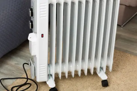 Radiador de aceite blanco con ruedas, mostrando cómo funciona un radiador de aceite al calentar la habitación.