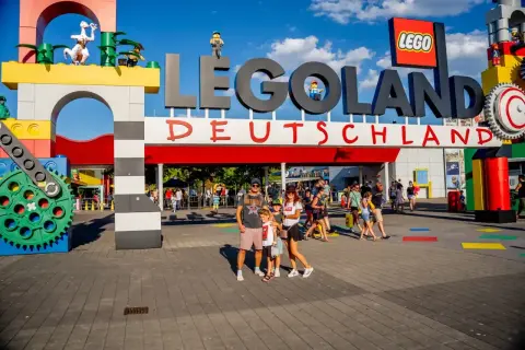 Rodzina pozuje przed wejściem do Lego Land Deutschland. Kolorowe klocki i wielkie logo zapraszają do świata zabawy.