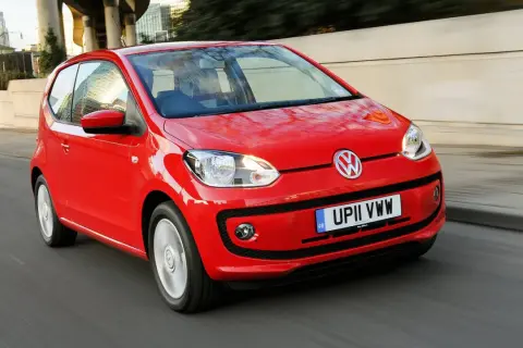 Czerwony Volkswagen Up w ruchu miejskim. Choć jego kompaktowe wymiary to zaleta, warto rozważyć potencjalne volkswagen up wady, jak ograniczona przestrzeń.