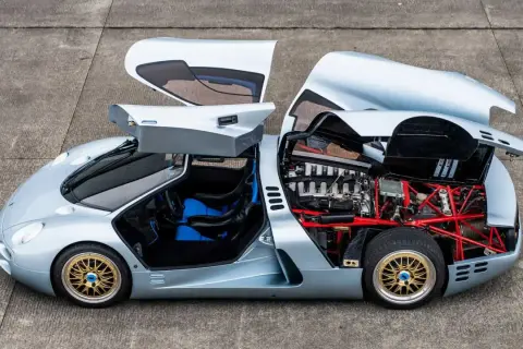 Der Isdera Commendatore 112i mit geöffneten Flügeltüren und Motorhaube zeigt seinen V12-Motor und die rote Gitterrohrrahmen-Konstruktion.