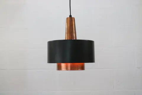 Stylowa lampa sufitowa z miedzi i czarnego metalu, dodająca ciepła wnętrzu.